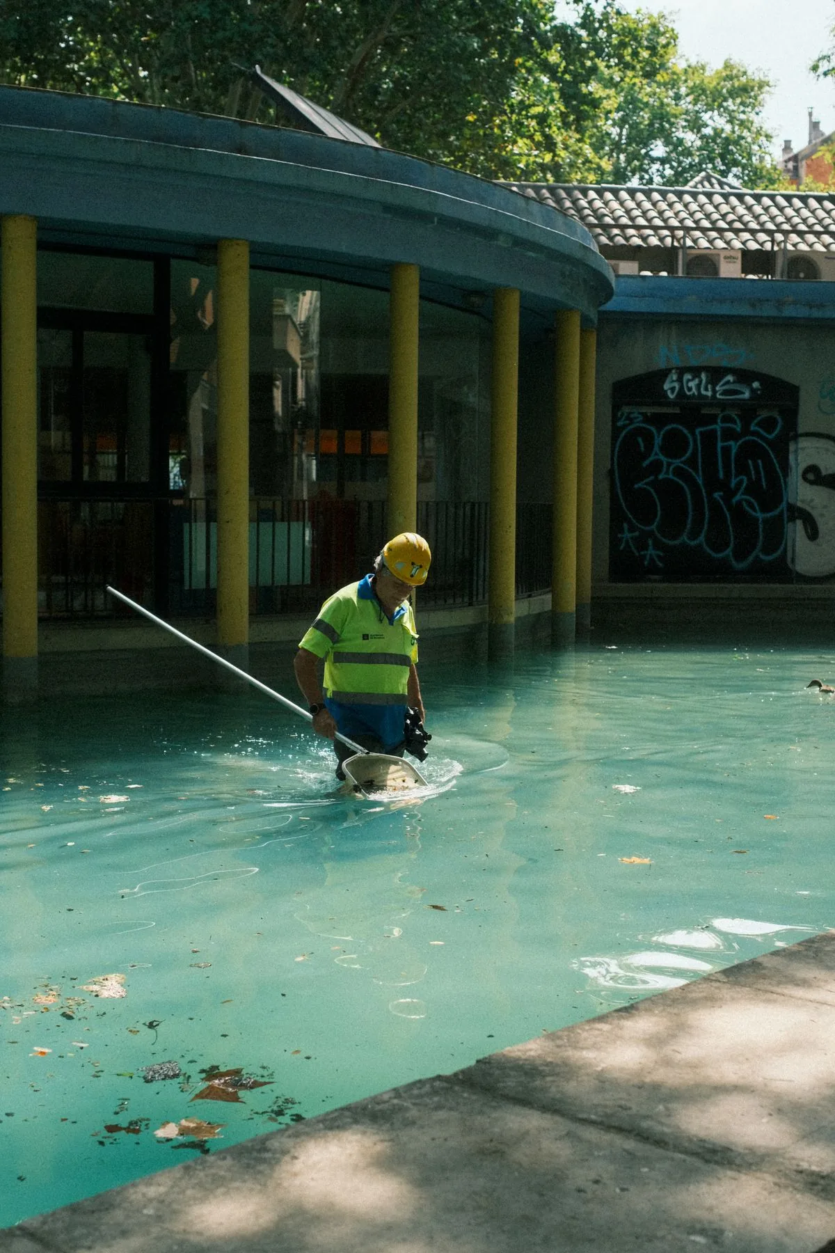 Trabajador limpiando una alberca. Imagen de referencia para una marca ficticia.