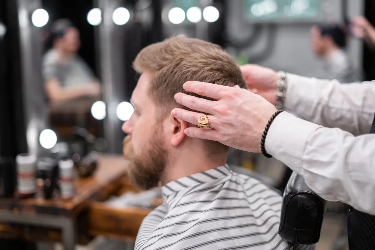 Barbero realizando un corte de cabello. Imagen de referencia para una marca ficticia.