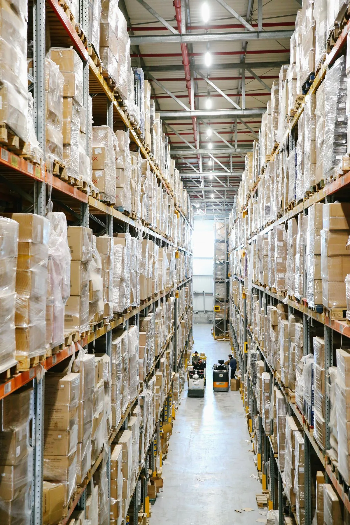 Pasillo de almacén con cajas organizadas en estantes. Imagen de referencia para una marca ficticia.