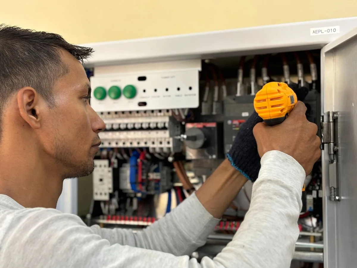Electricista trabajando en un tablero eléctrico. Imagen de referencia para una marca ficticia.