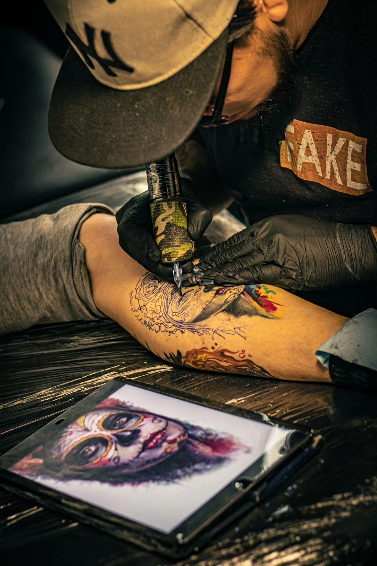 Artista realizando un tatuaje en un estudio. Imagen de referencia para una marca ficticia.