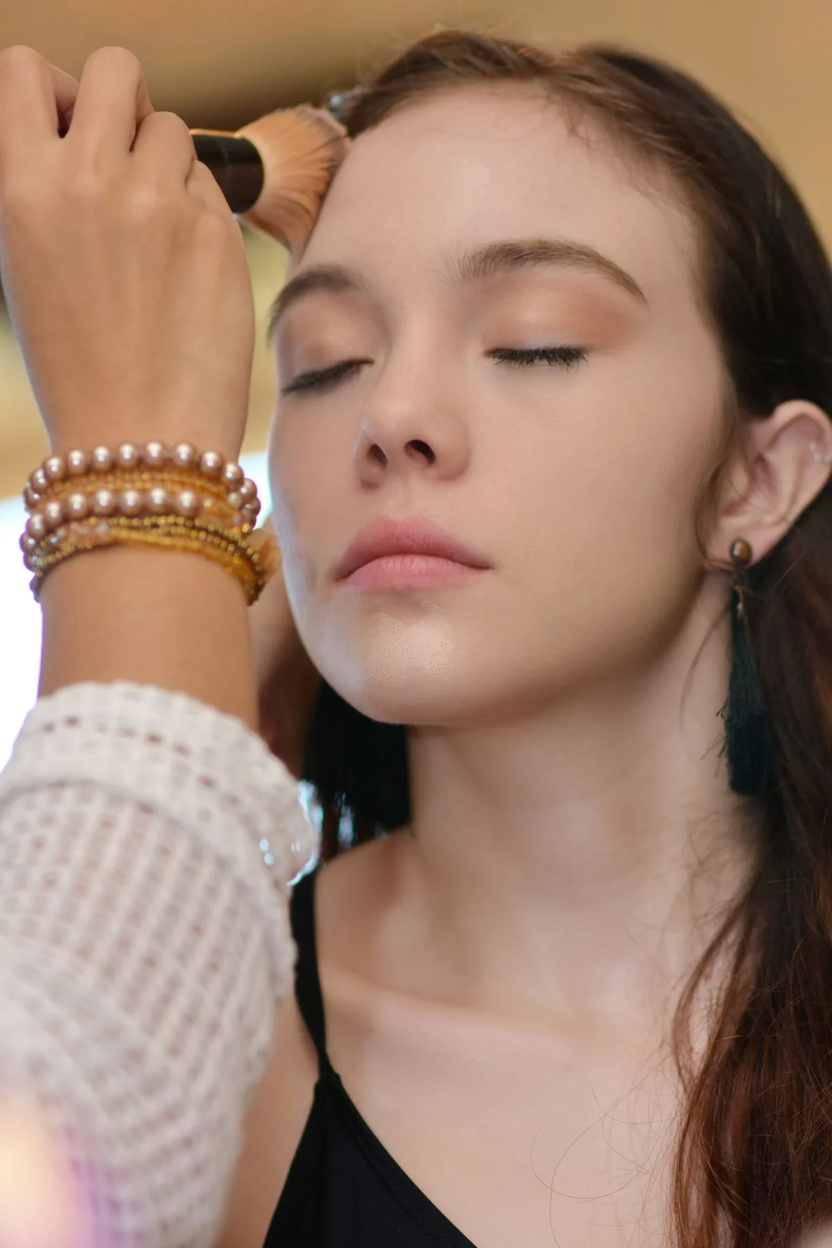 Maquillista aplicando maquillaje con una brocha. Imagen de referencia para una marca ficticia.