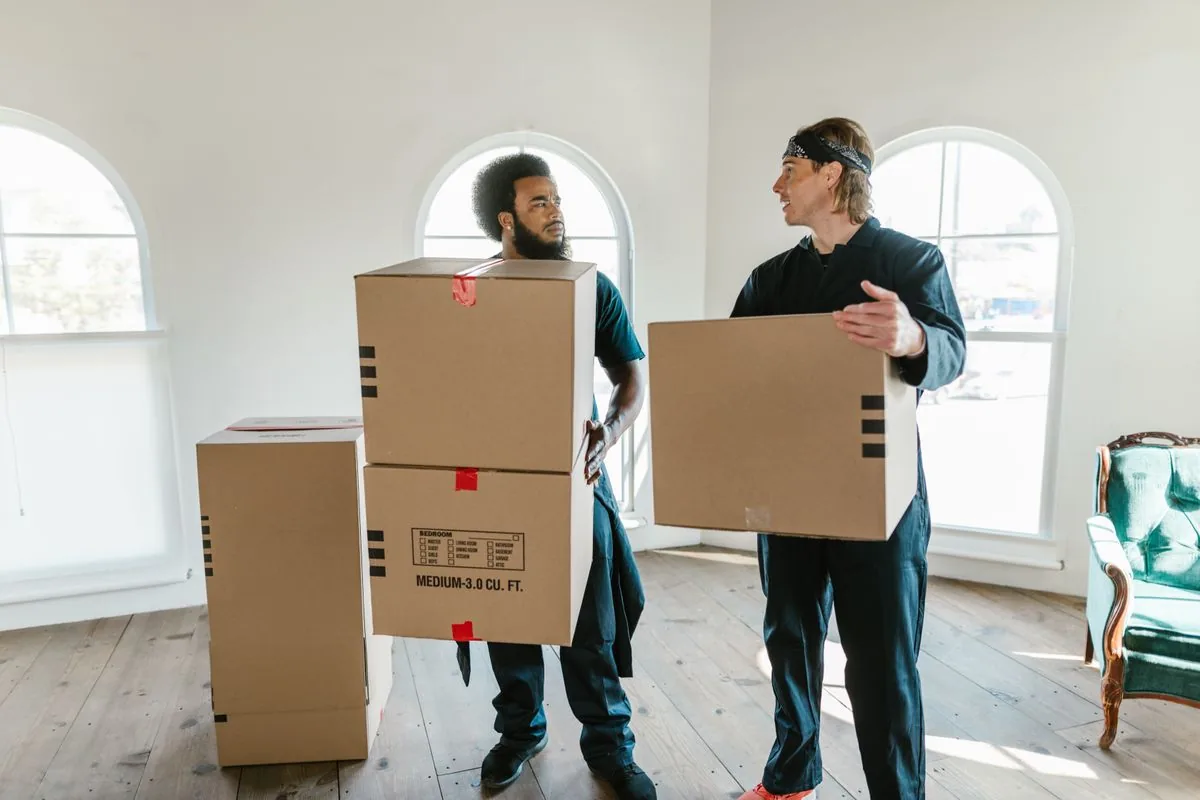 Trabajadores trasladando cajas de cartón. Imagen de referencia para una marca ficticia.