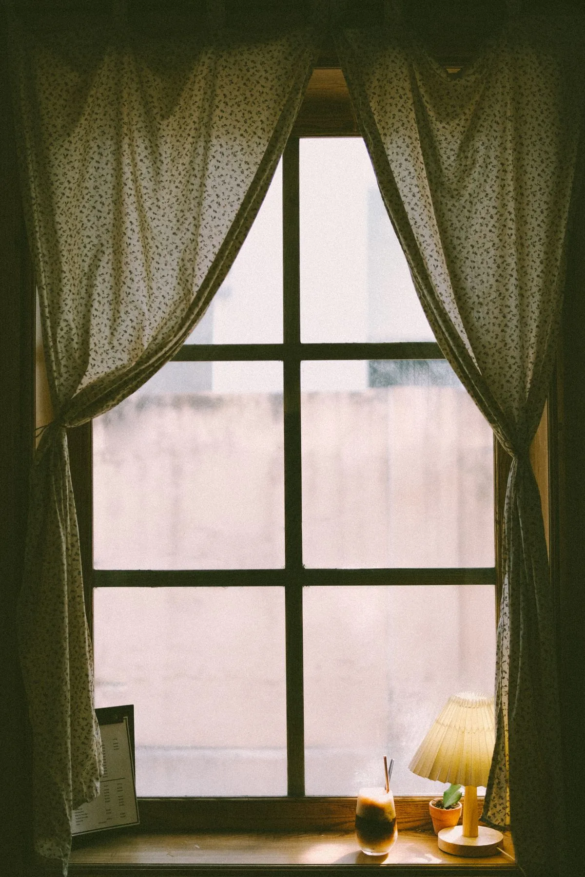 Cortinas junto a una ventana iluminada. Imagen de referencia para una marca ficticia.
