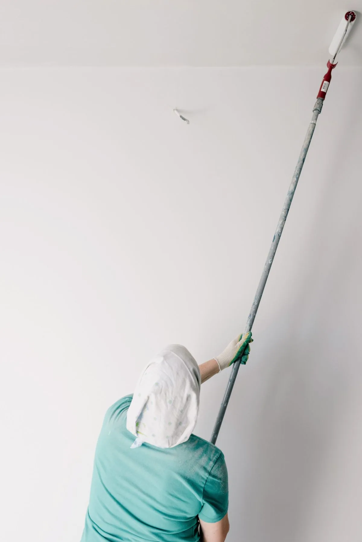 Pintor aplicando pintura con rodillo en una habitación. Imagen de referencia para una marca ficticia.
