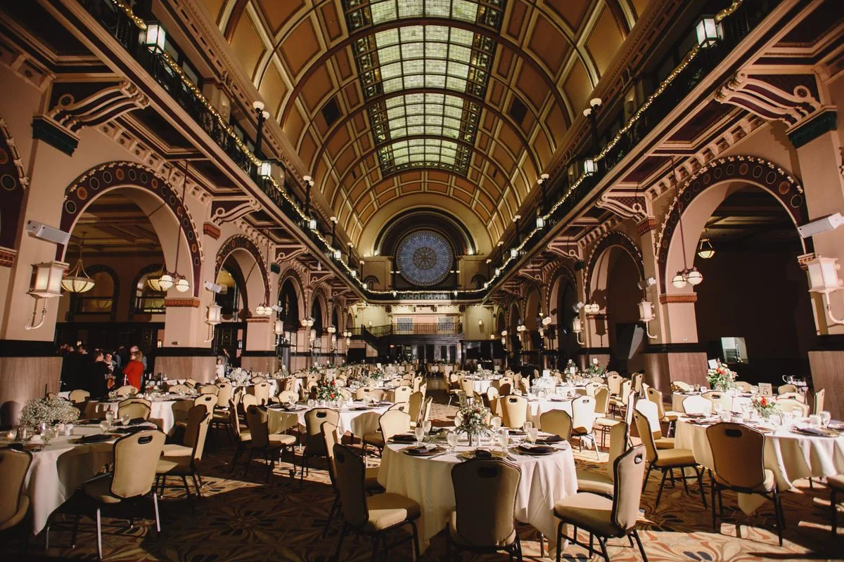 Mesas y sillas distribuidas en un salón de eventos. Imagen de referencia para una marca ficticia.