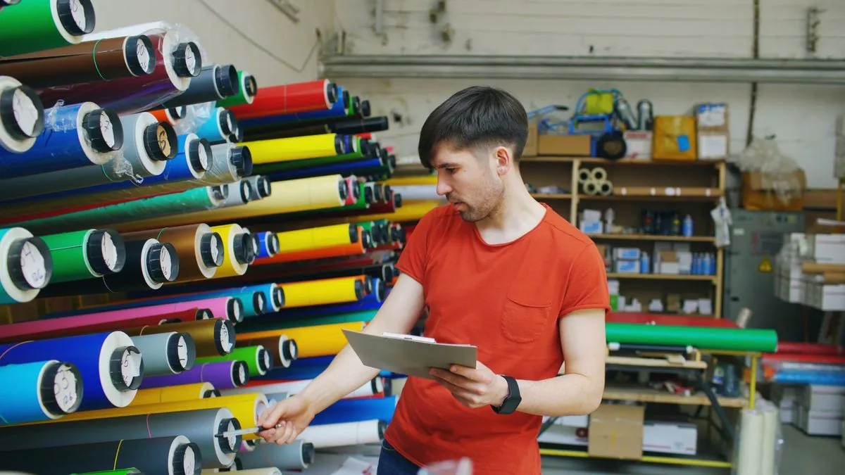 Revisión de rollos de vinilo de colores en un almacén. Imagen de referencia para una marca ficticia.