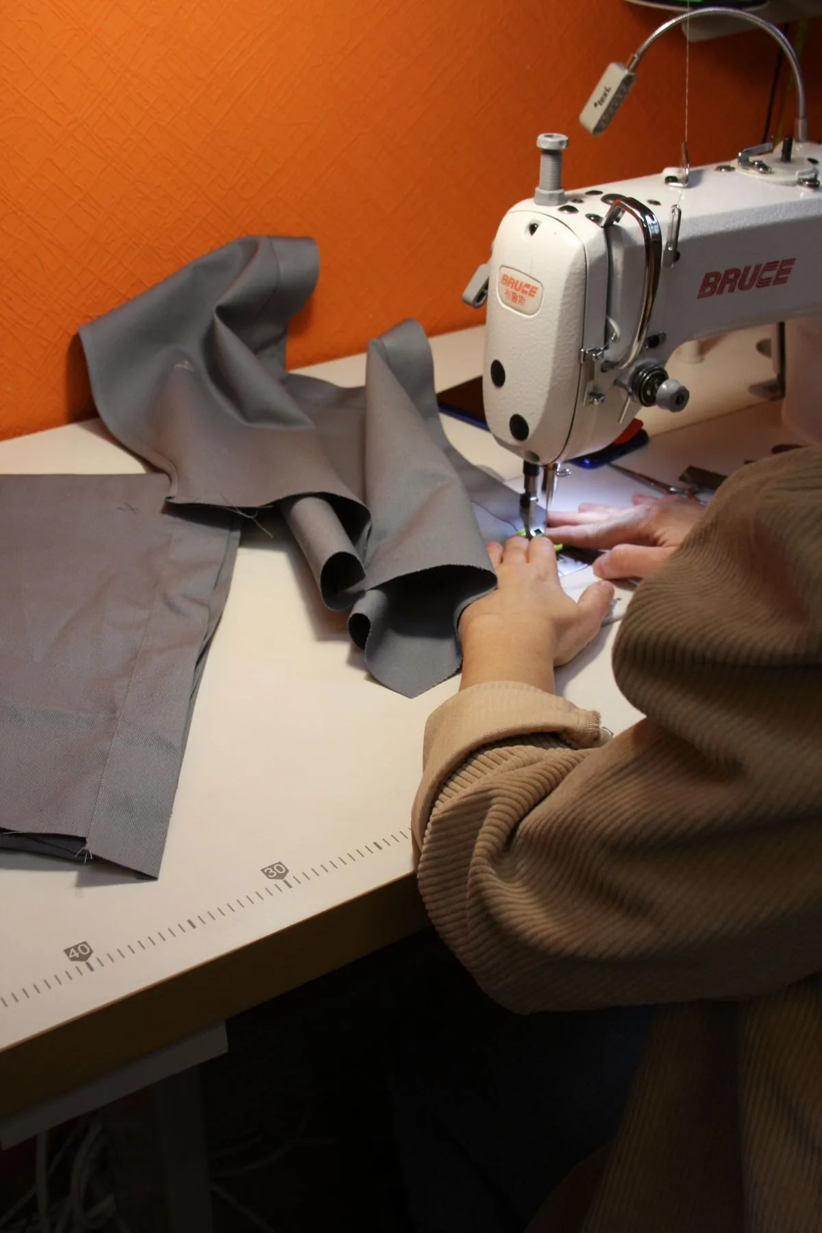 Persona cosiendo una prenda con máquina de coser. Imagen de referencia para una marca ficticia.