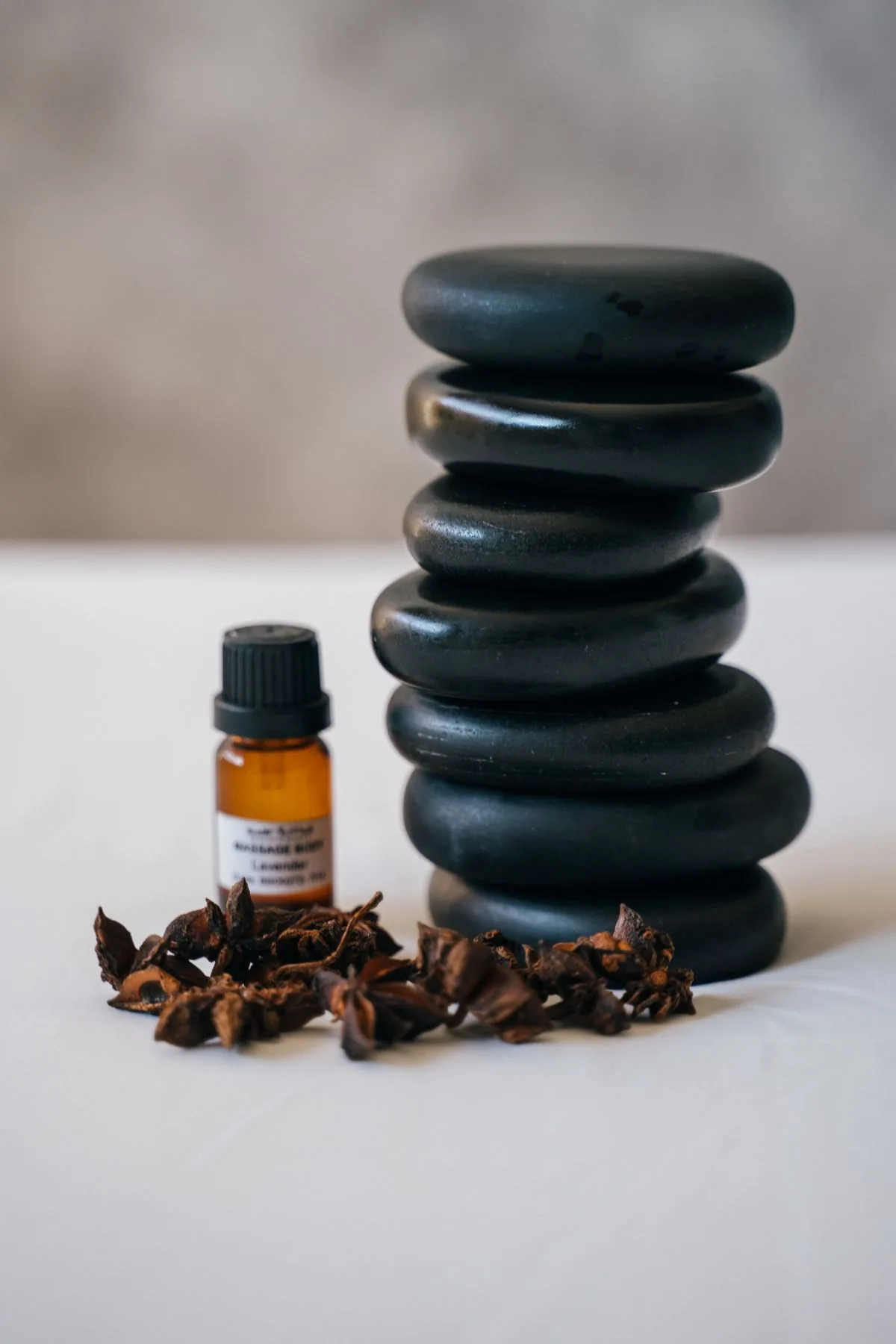 Piedras de masaje y aceite sobre una superficie clara. Imagen de referencia para una marca ficticia.