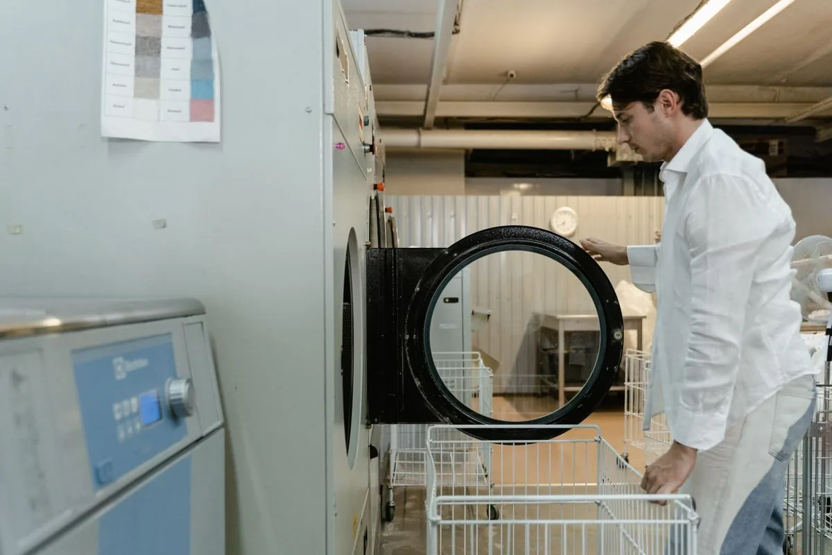 Trabajador atendiendo el proceso de lavado de prendas. Imagen de referencia para una marca ficticia.